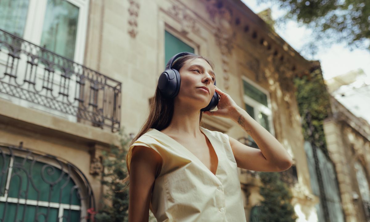 Frau mit Bluetooth-Kopfhörern vor historischem Gebäude – moderne Technik im Alltag.