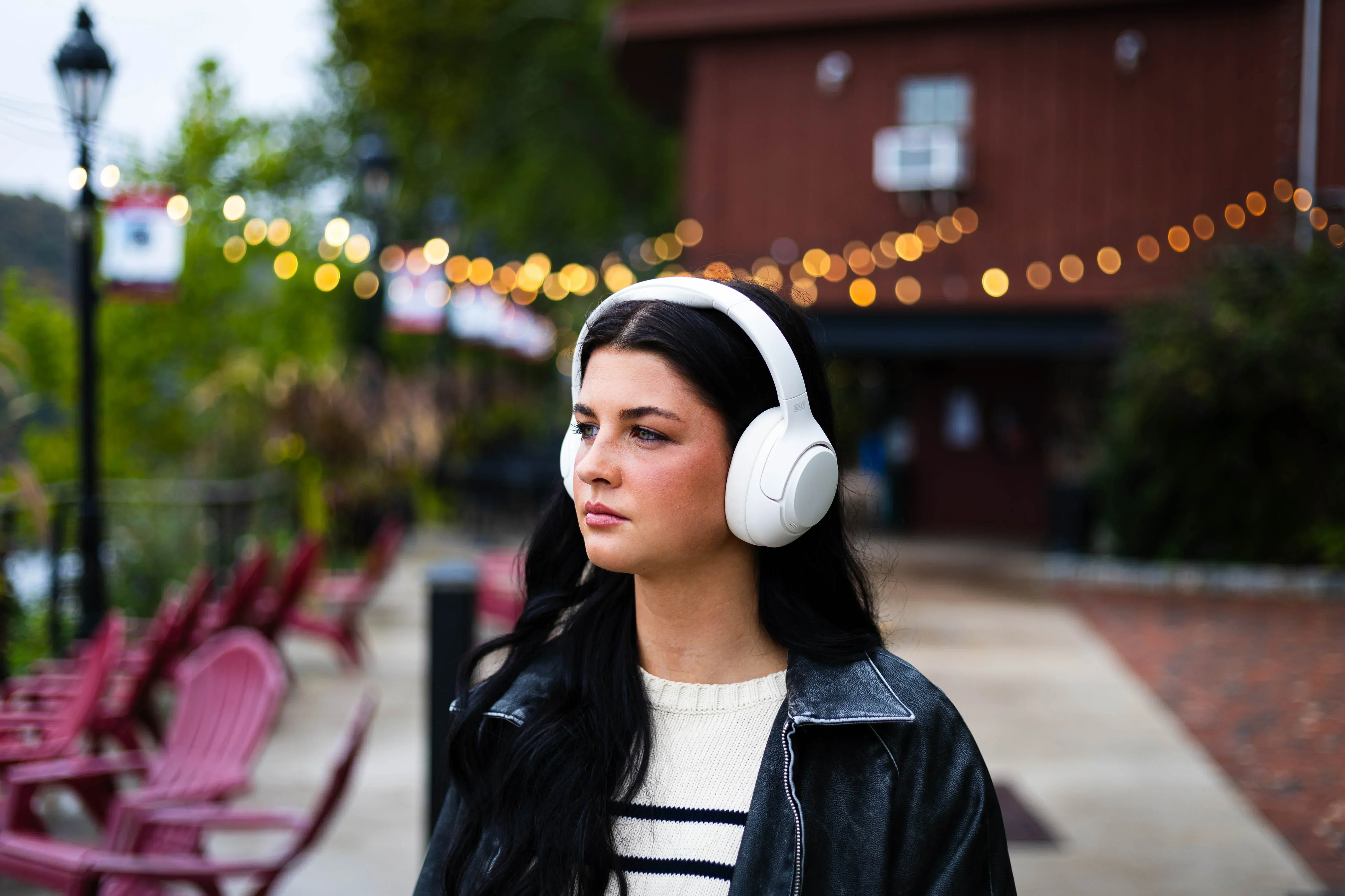 Frau mit weißen Bluetooth-Kopfhörern im Freien – Unterschied zu kabellosen Modellen erklärt.