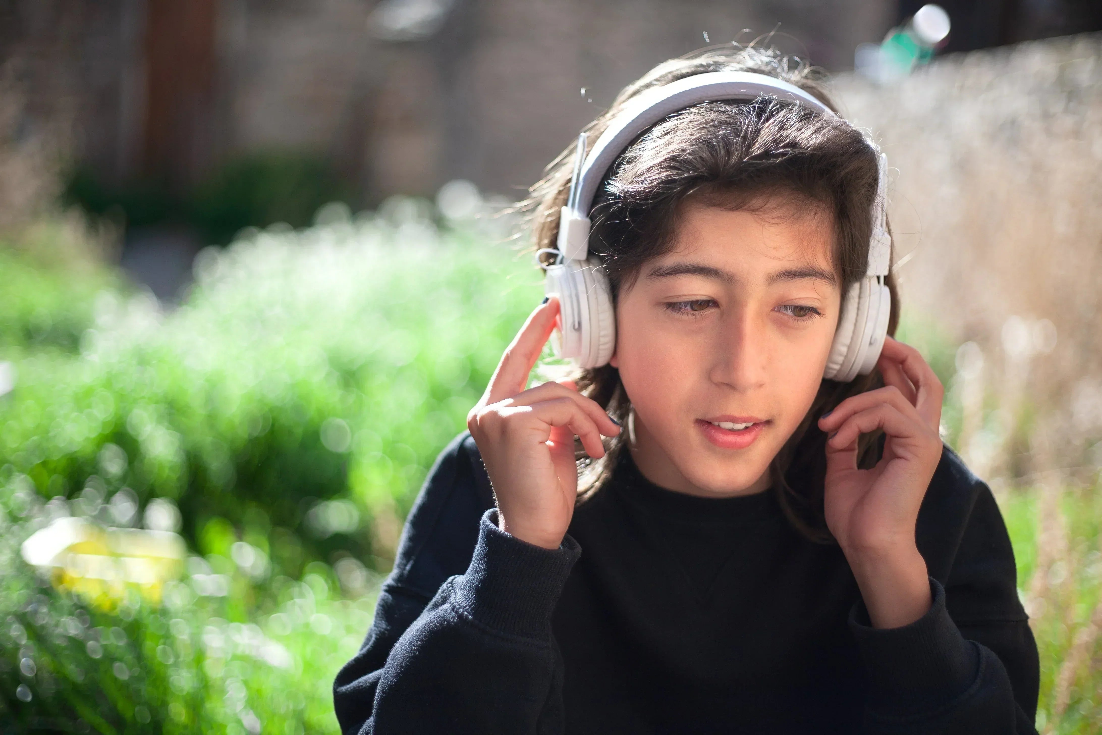 Junge trägt weiße Over-Ear-Kopfhörer im Freien – Testet Komfort & Trageerlebnis bei Sonnenschein.