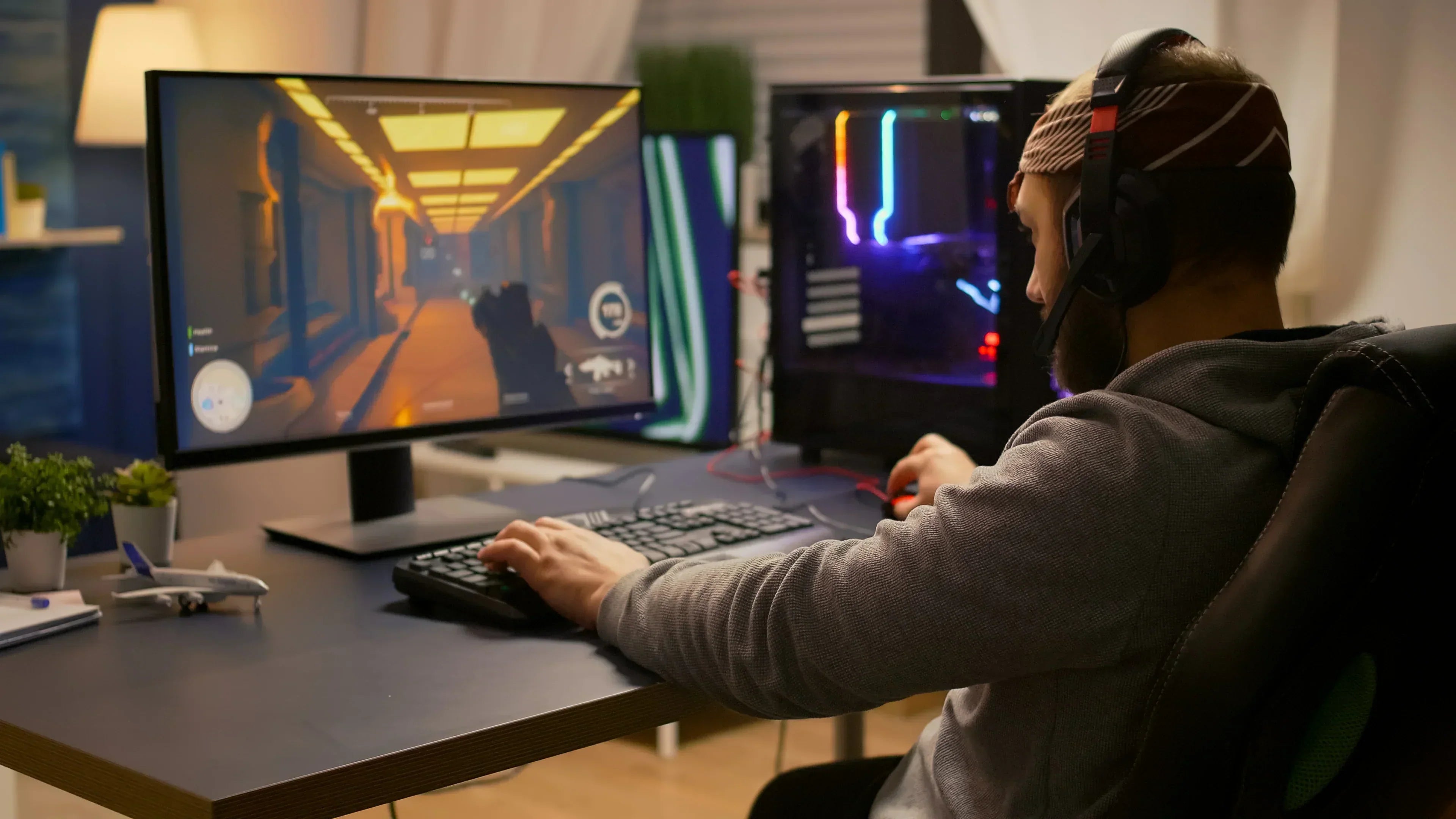 Gamer mit Headset spielt Shooter am PC mit RGB-Beleuchtung – niedrige Latenz für optimale Performance im Gaming-Modus.