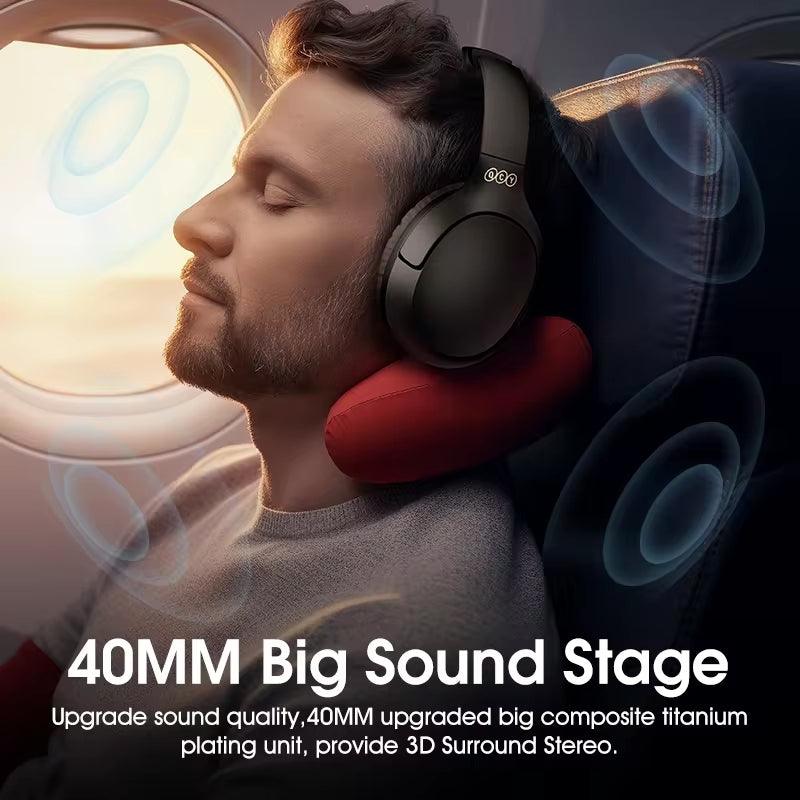 Auscultadores QCY H2 Pro pretos, usados por uma pessoa num avião, destacando o espaço sonoro de 40 mm e o som estéreo surround 3D.