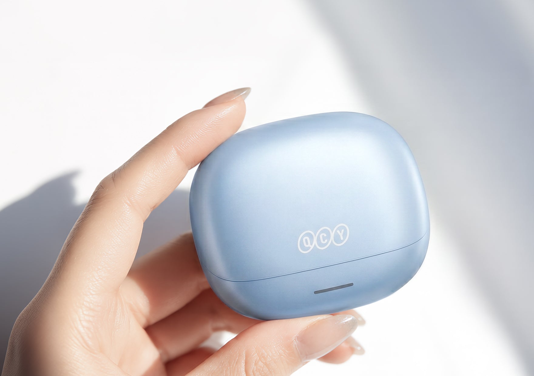 Auriculares Bluetooth QCY em azul claro, guardados na caixa de carregamento.