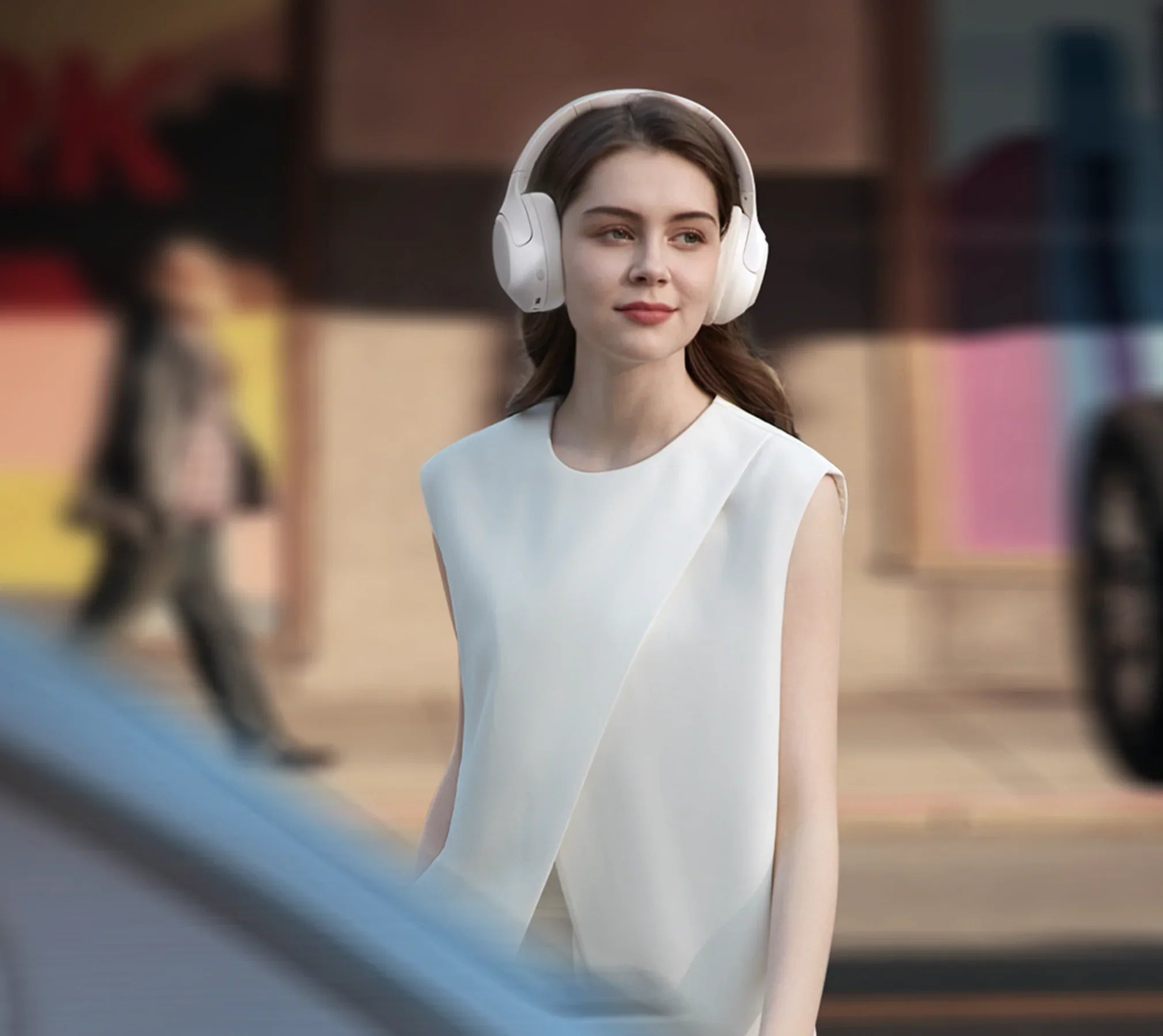 Mulher com auscultadores over-ear brancos em ambiente urbano, moda elegante, tecnologia moderna