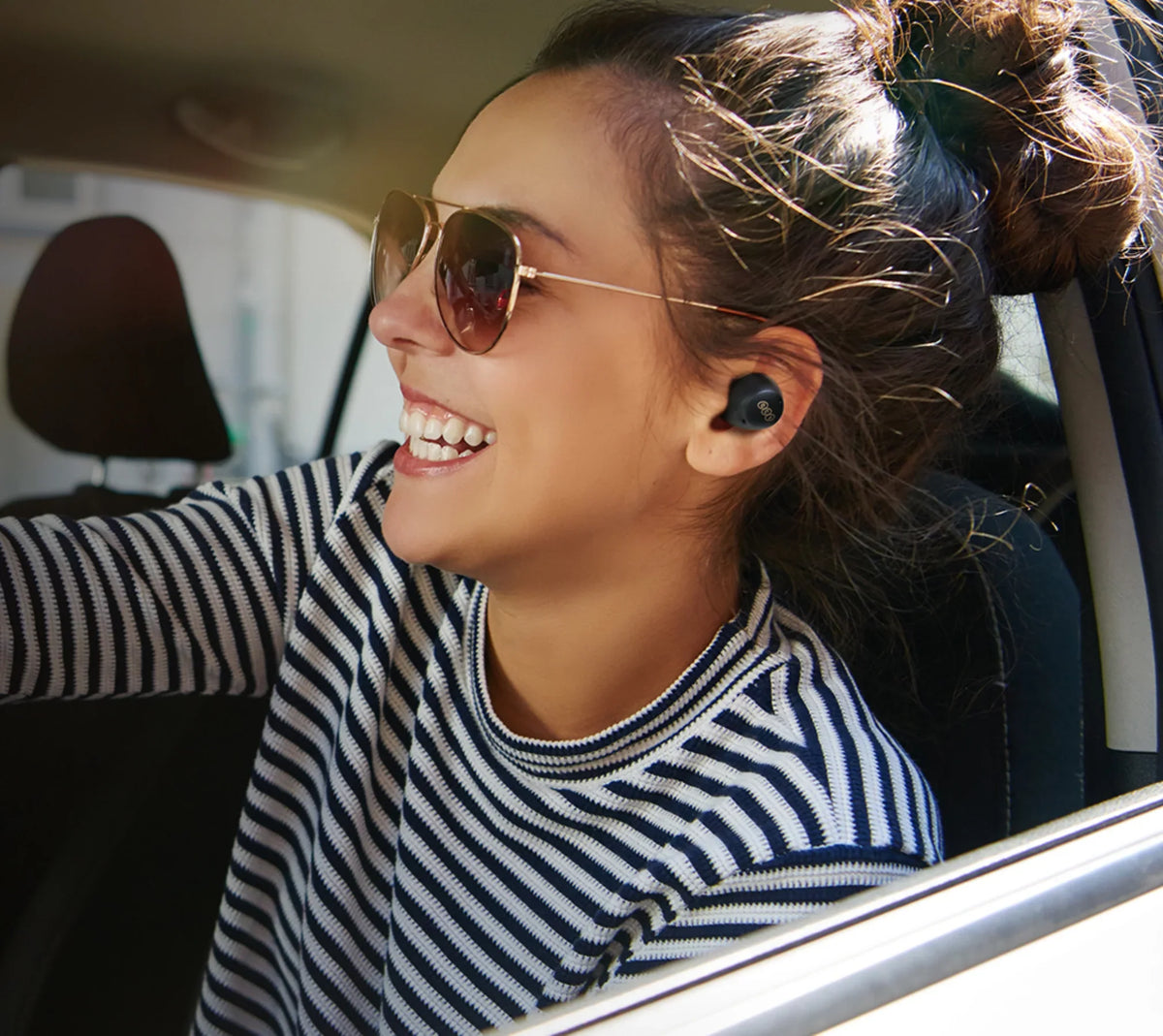 Mulher com óculos de sol e auriculares sem fios no carro