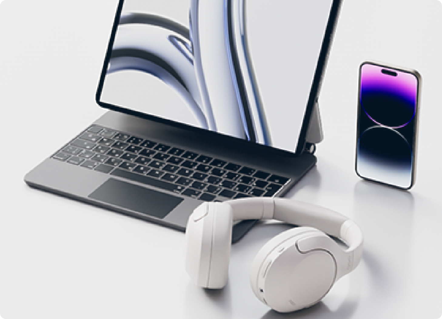 Conjunto moderno de portátil com auscultadores brancos e smartphone sobre uma mesa clara.