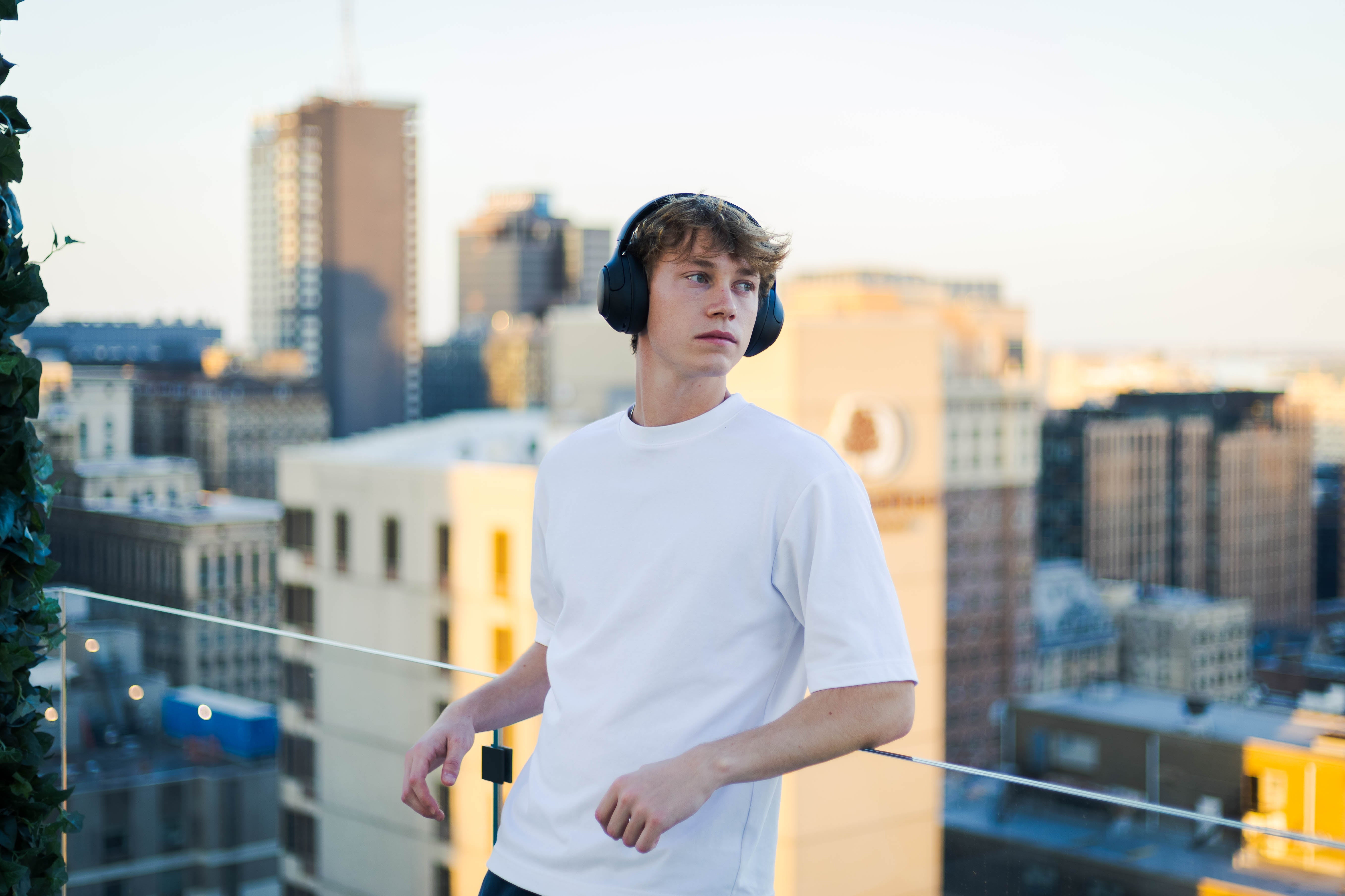 Jovem homem com auscultadores no terraço com vista para a cidade